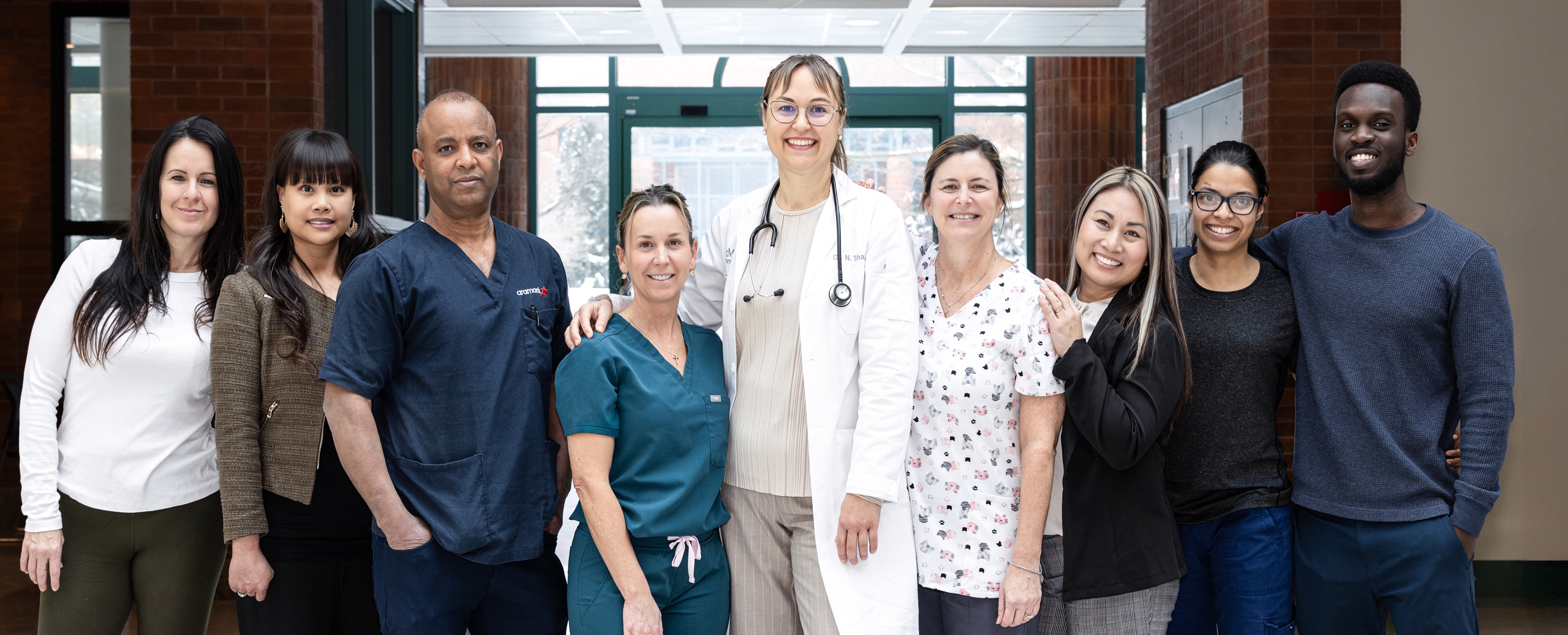 A patient receives medical treatment in a clinic, seated beside a smiling healthcare worker.