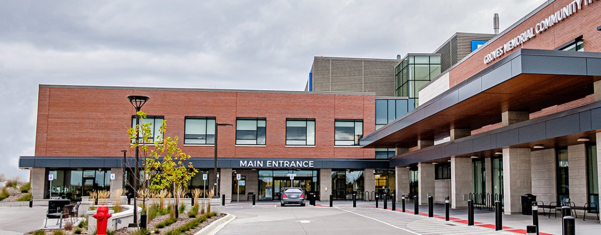 The main entrance of a modern brick building with large windows and a covered drop-off area.