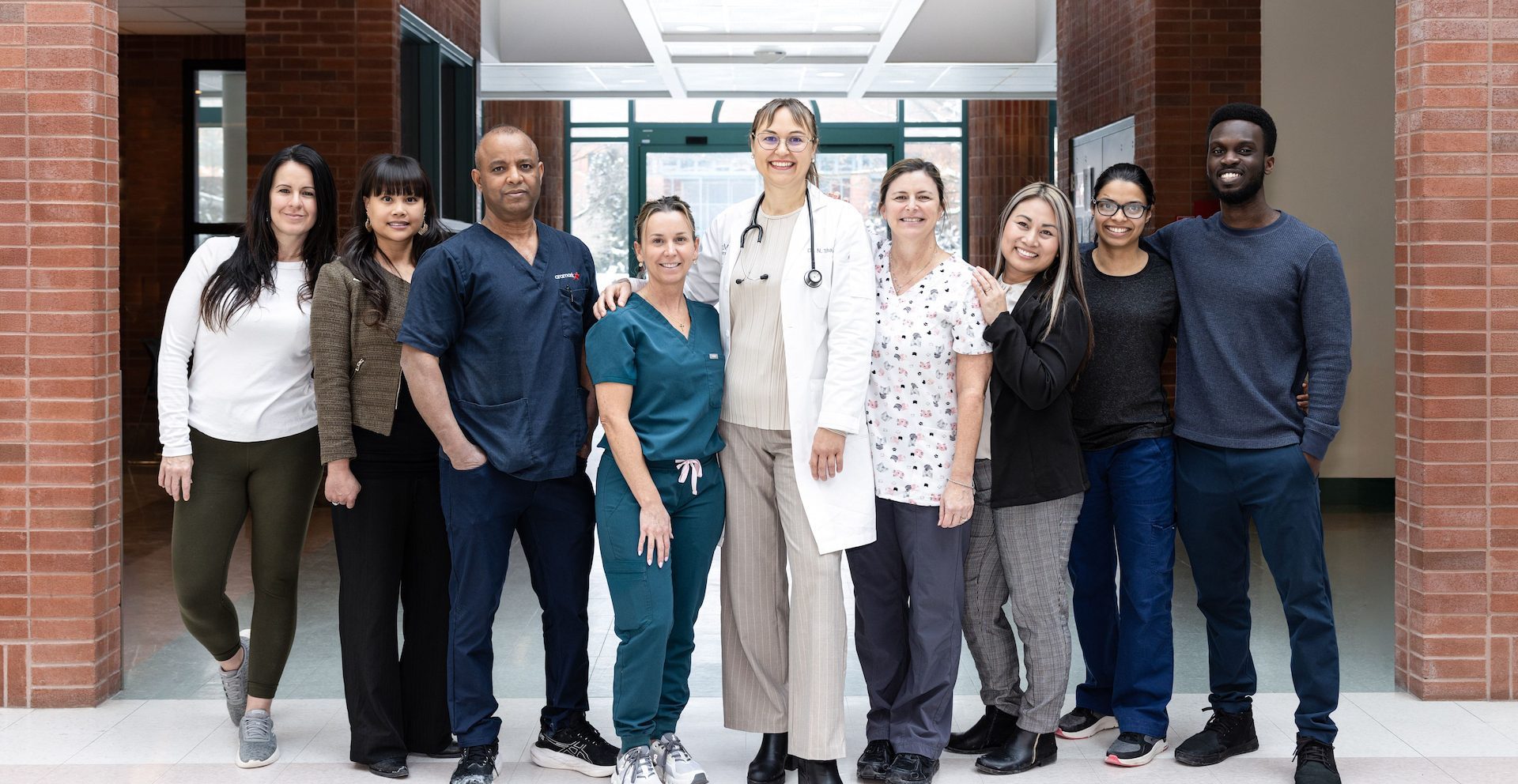 Un grupo diverso de profesionales sanitarios posa juntos en el pasillo de un hospital, sonriendo a la cámara.