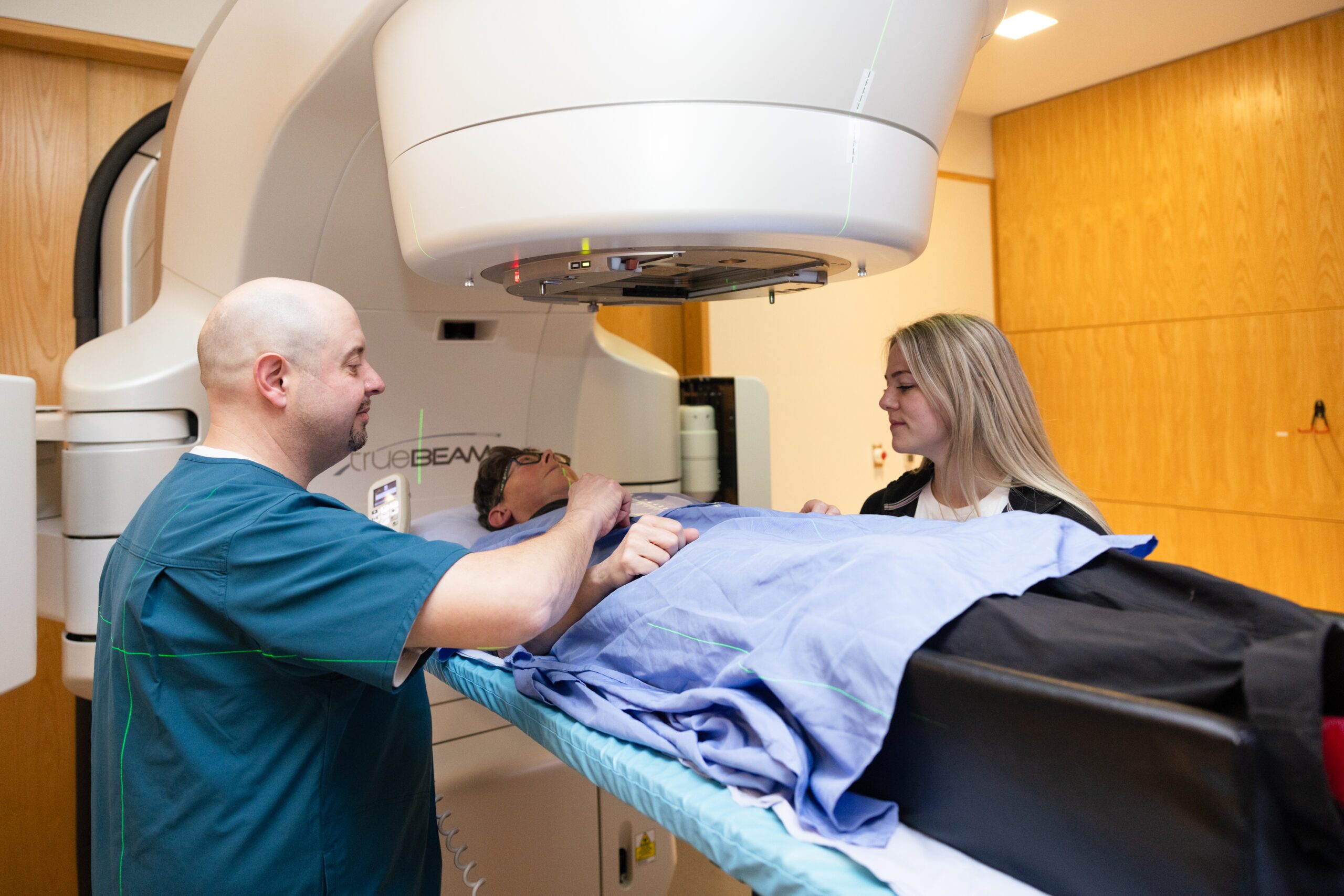 Two Radiation Therapists setting a patient up for radiation treatment on a machine.