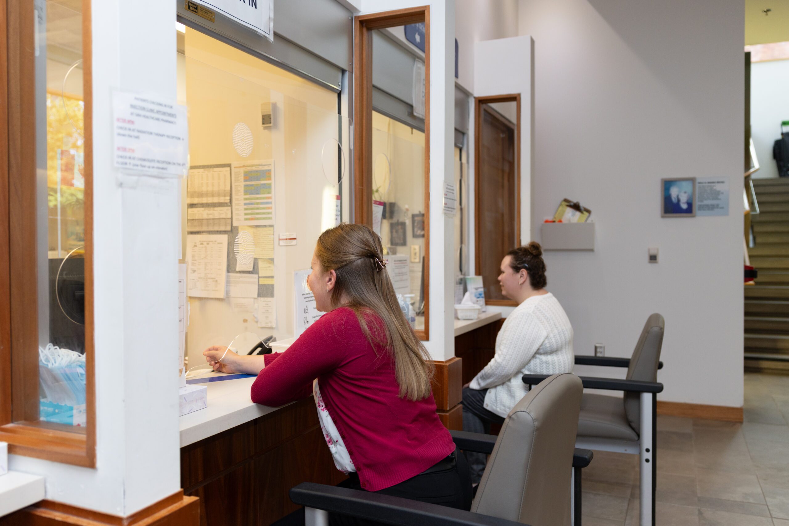 Two patients sitting at registration desks.