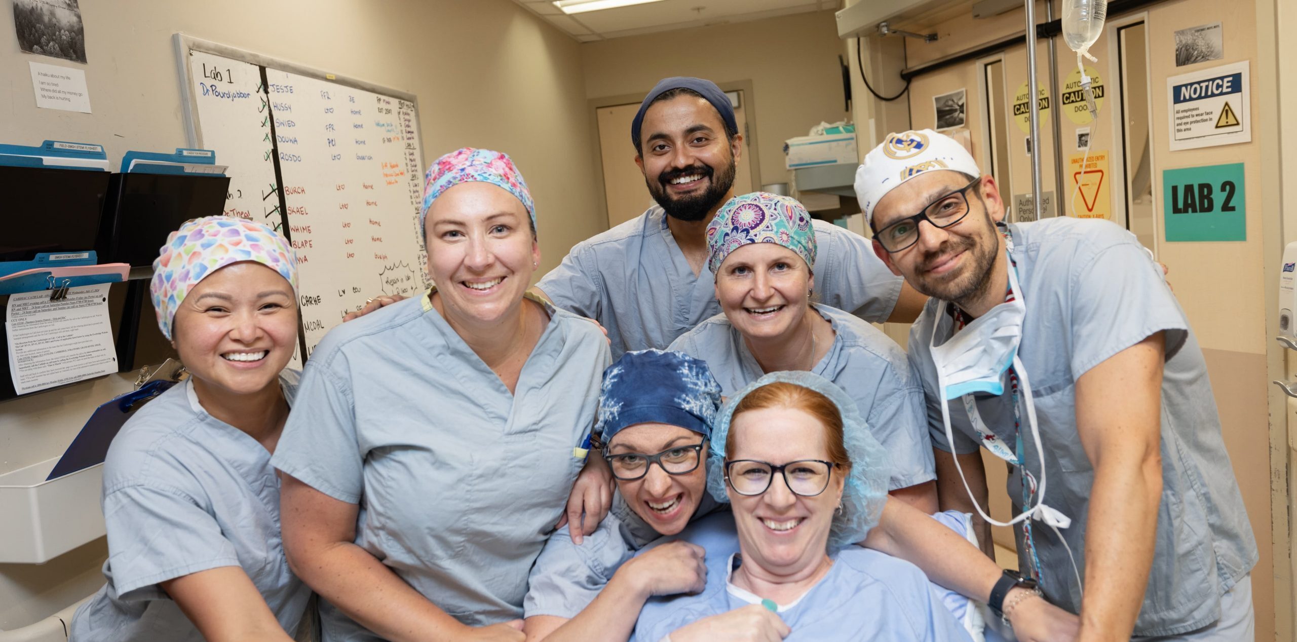 Un groupe de professionnels de santé sourit autour d'un patient dans un environnement hospitalier.